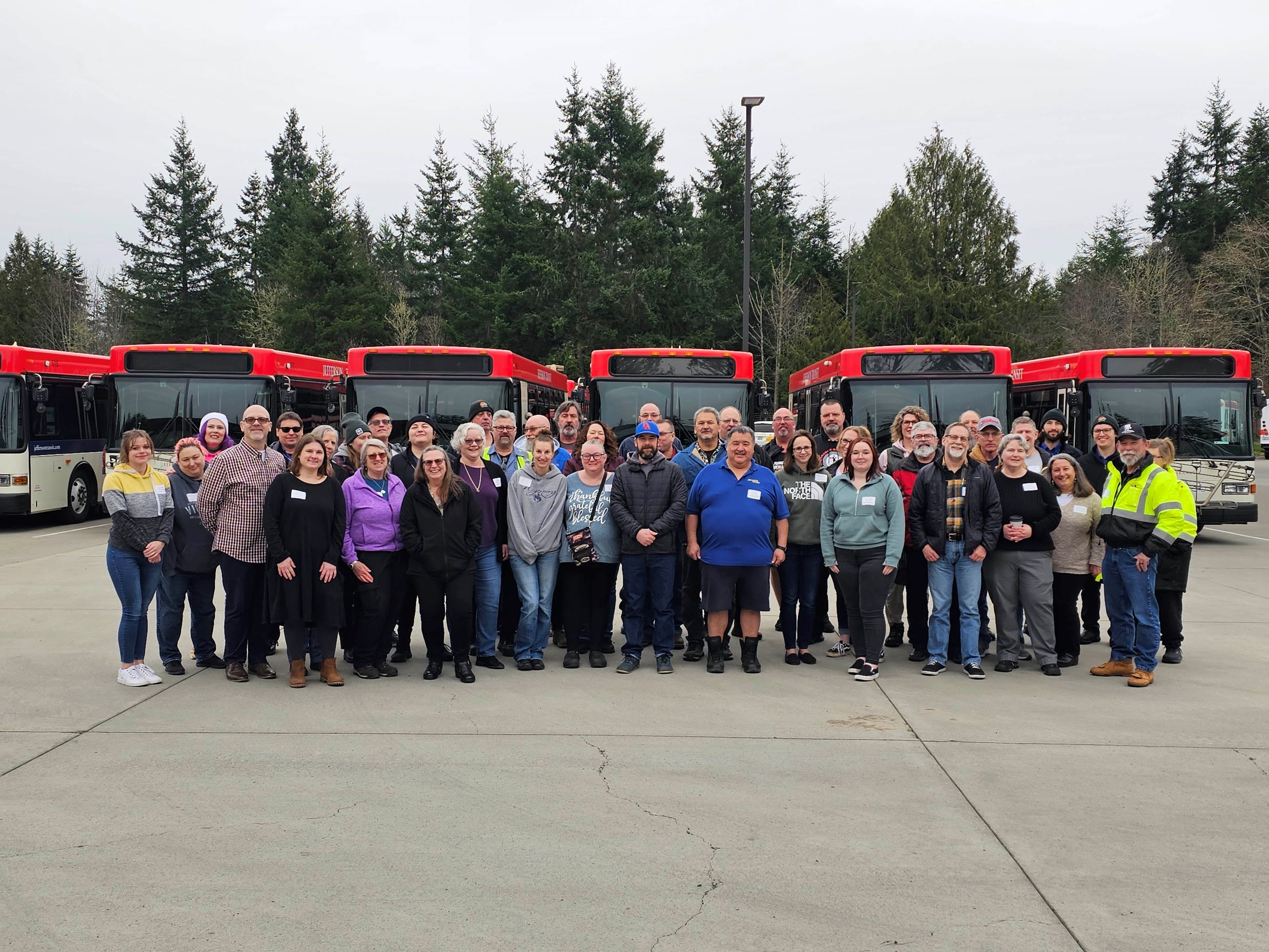 JTA staff standing in front of buses in bus barn for a group photo
